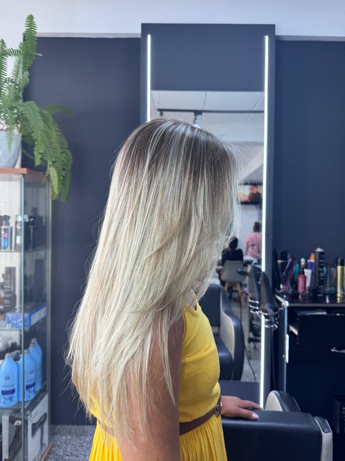 Madeixas loiras com transição suave desde a raiz e acabamento liso.